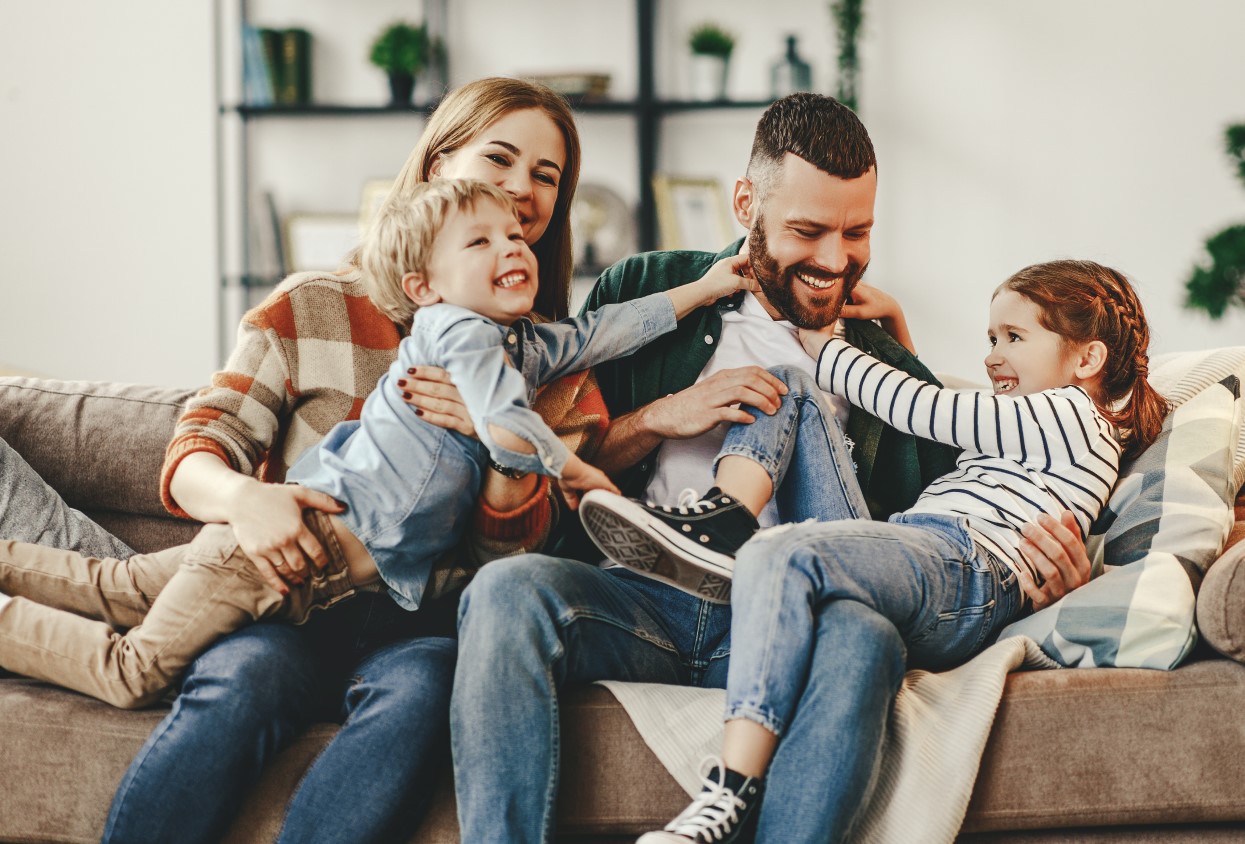 happy family mother father and kids at home on couch